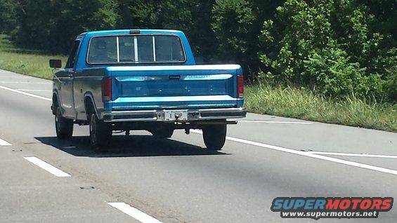 Rear view of a blue 1980s pickup truck on highway