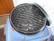 2004 Aston Martin Virage - A close-up view of a round grill grate with a black rim, resting on a blue plastic container.