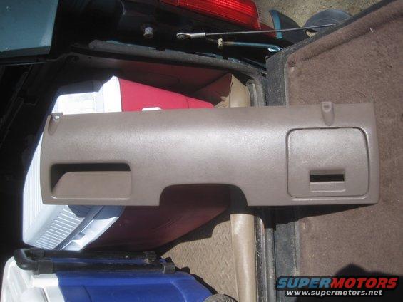 Tan dashboard trim piece with two storage compartments, one with a rectangular slot