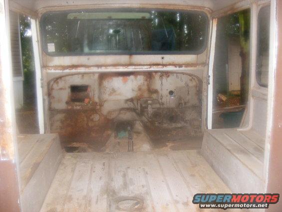 Interior view of a rusty, empty vehicle with wooden floor and bench seats
