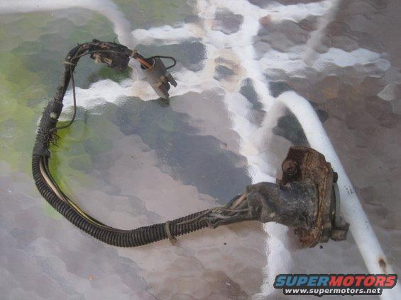 Wiring harness with connectors and frayed insulation, resting on a textured surface