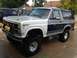 1986 Ford Bronco - A two-tone Ford Bronco with a white fender and yellow fog lights sits in a driveway.