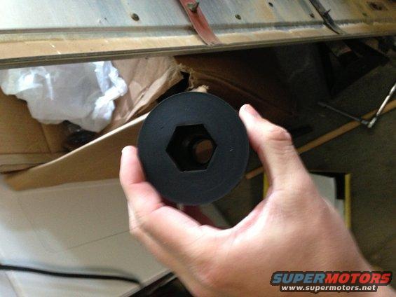 Black hexagonal part held in hand, with Supermotors logo visible