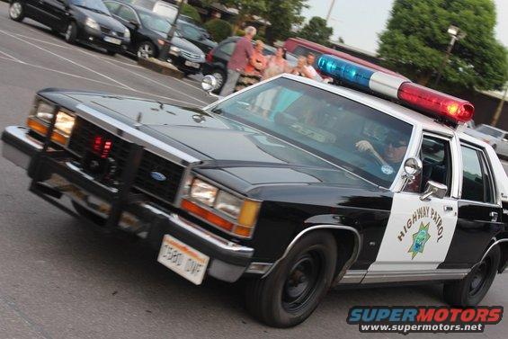 Black and white police car with light bar, "HIGHWAY PATROL" text on door, and California seal