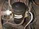 1994 Ford Bronco - Close-up view of a black cylindrical engine component with visible white stripes and a small blue emblem on top.