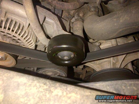 Close-up of an engine belt tensioner pulley and serpentine belt