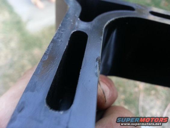 Close-up of a dark metal engine part with internal channels, held by a hand