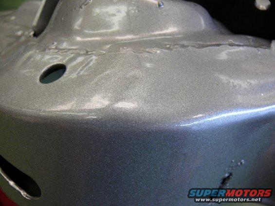 Close-up of metallic gray painted car part with visible welds and holes