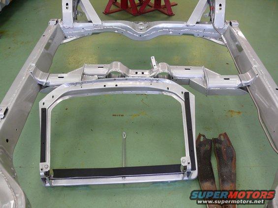 car frame on green floor, some rusty parts nearby