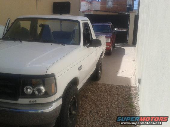 White 1992 Ford F-150 pickup truck, 3/4 front view, parked next to a red SUV