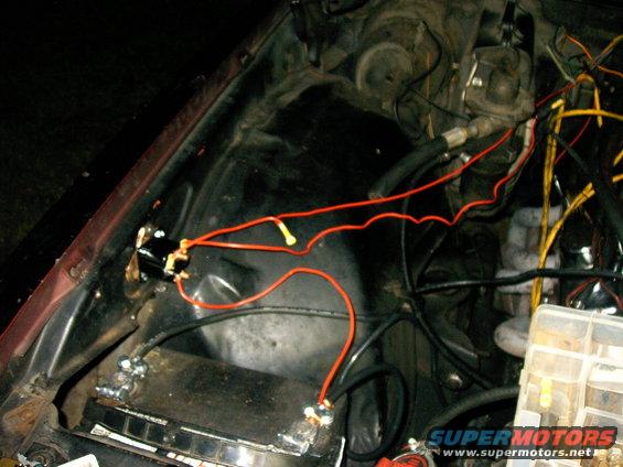 Engine bay with red and yellow wires connected to a black relay and battery terminals