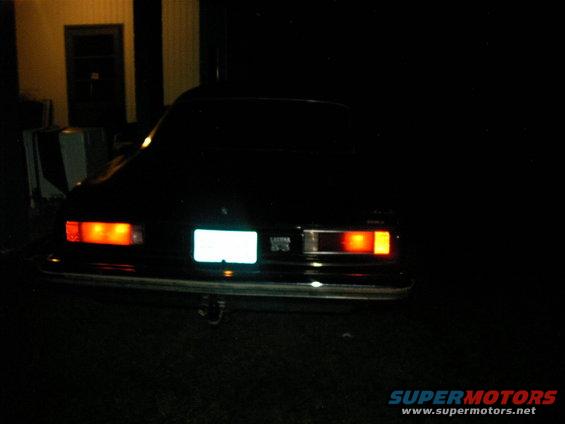 Black sedan's rear end with illuminated taillights and a blank license plate