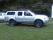 2003 Nissan Frontier - This silver 2003 Nissan Frontier pickup truck is equipped with a cap and roof rack, seen from the side.