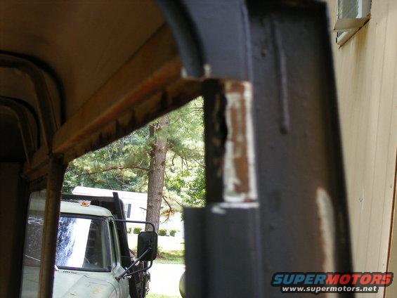 View through a truck's cab frame showing part of the interior and another truck outside