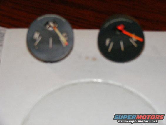 Two round gauges, one gray and one black, with needles pointing to different levels. Text 'F' and 'E' are visible on the gray one