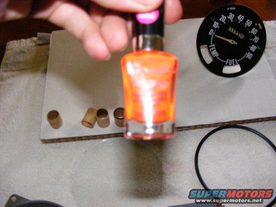 Gauge with temperature and fuel readings, next to orange nail polish bottle