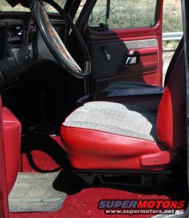 Interior shot of a red truck cab, showing the driver's seat, steering wheel, and door panel
