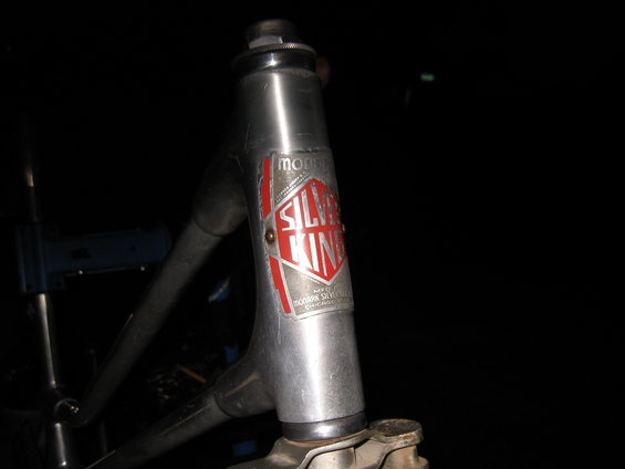 Close-up of a silver bicycle head tube with a red and silver 'Silver King' badge. Text below says 'MFG. BY MONARK SILVER KING CHICAGO'