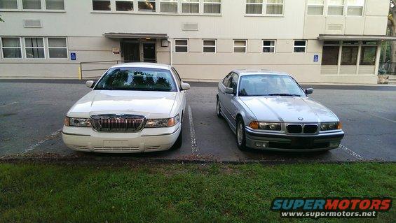Silver 1997 BMW 3 Series front view, parked next to a Mercury Grand Marquis