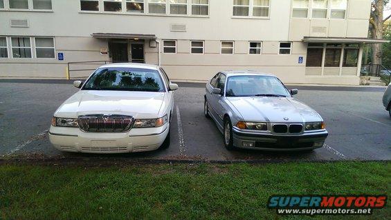 Silver 1997 BMW 3 Series parked next to a white Mercury Grand Marquis