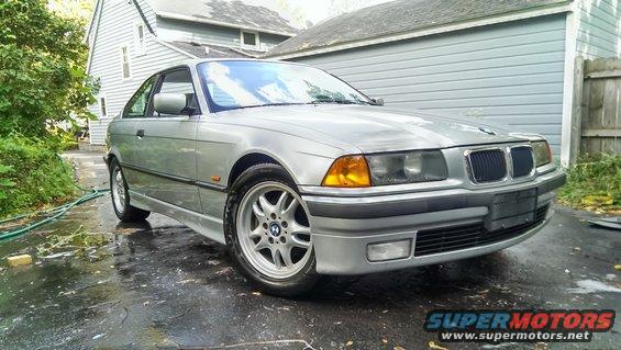 Silver 1997 BMW 3 Series coupe parked on a wet driveway, front 3/4 view