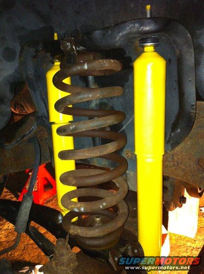 close-up of rusty coil spring and two yellow shock absorbers