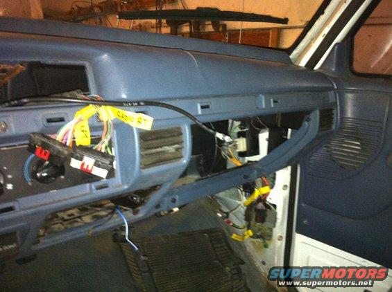 Dashboard wiring harness with yellow tags, vents, and open glove compartment