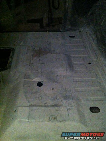 Vehicle interior floor, light colored, showing structural ribs and some rust spots