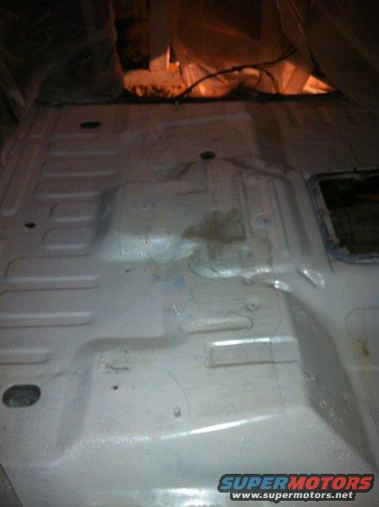 Interior floor pan of a vehicle, possibly undergoing restoration or cleaning. Some staining is visible