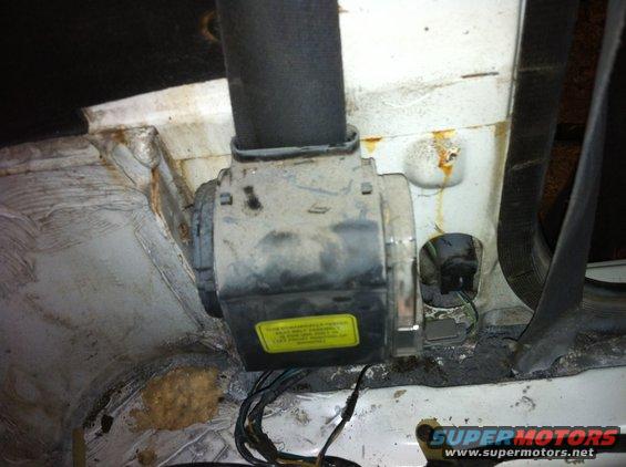 Close-up of a dusty automotive component with a yellow warning sticker and wiring