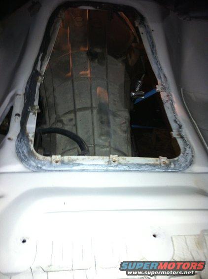 View into vehicle transmission tunnel, showing the drivetrain components