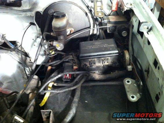 Engine bay with brake fluid reservoir and fuse box visible. Lots of wires and hoses