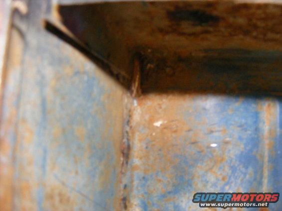 Close-up of a rusted metal corner with blue paint. Supermotors.net logo visible