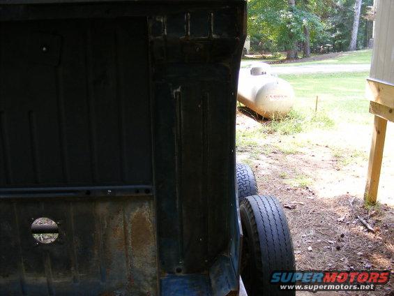Looking into the dark interior of a vehicle bed, with tires and a propane tank visible outside