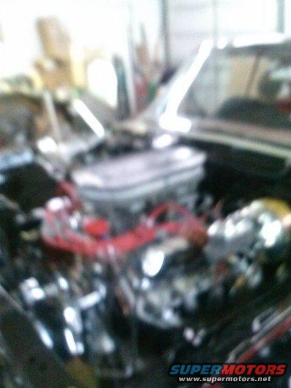 Engine bay with a carburetor and red spark plug wires
