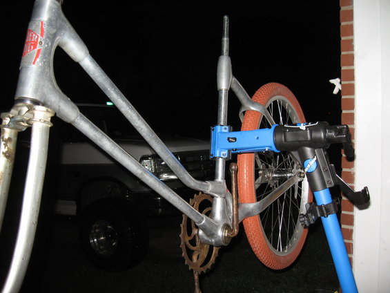 Aluminum bicycle frame with orange tire on repair stand