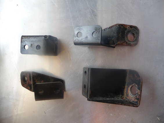 Four metal seat mount brackets on a metallic surface