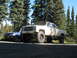 1989 Chevrolet C/K Pickup - A lifted white Chevrolet pickup truck is parked next to a blue SUV in a wooded area.