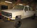 1989 Chevrolet C/K Pickup - This lifted pickup truck is in a garage, possibly undergoing modifications or repairs.