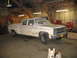 1989 Chevrolet C/K Pickup - A white pickup truck is parked inside a garage, partially covered in snow, with a dog looking at the camera.