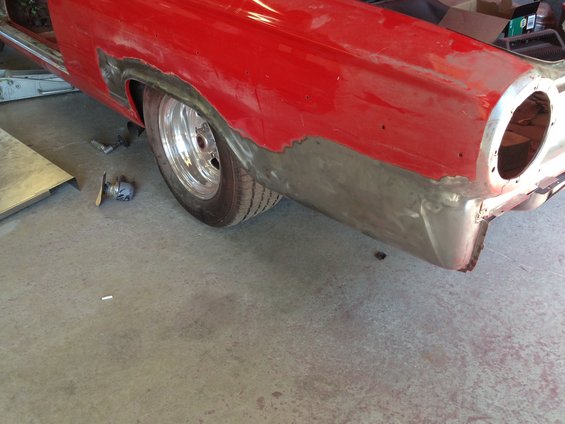 1964 Ford Fairlane rear quarter panel with exposed metal and chrome wheel