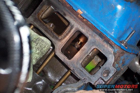 Engine intake manifold with green fluid visible in one cylinder opening