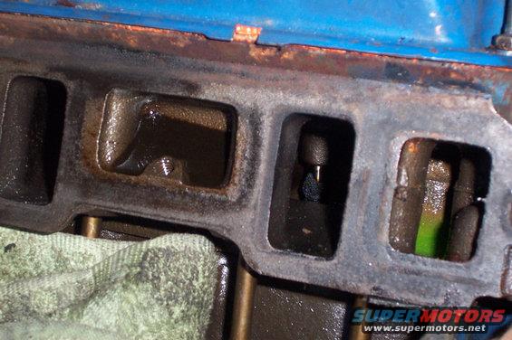 Close-up of engine intake manifold ports with visible oil and some green fluid