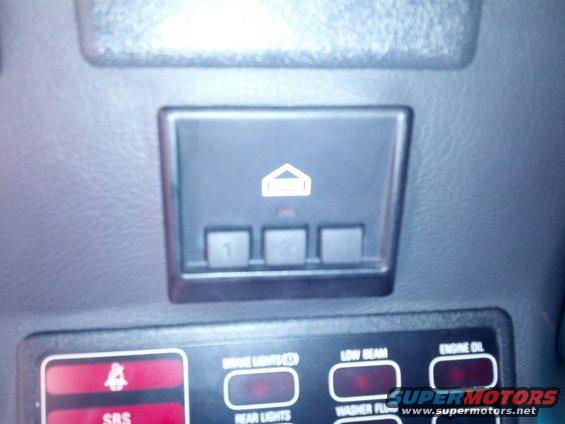 Car dashboard with buttons for garage door opener and various car functions like brake lights and low beam