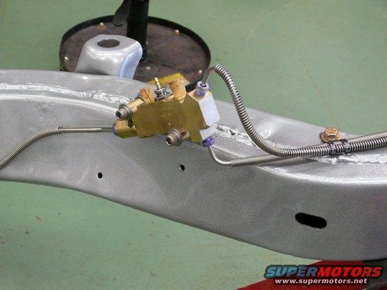 Brake proportioning valve attached to a silver vehicle frame with metal brake lines