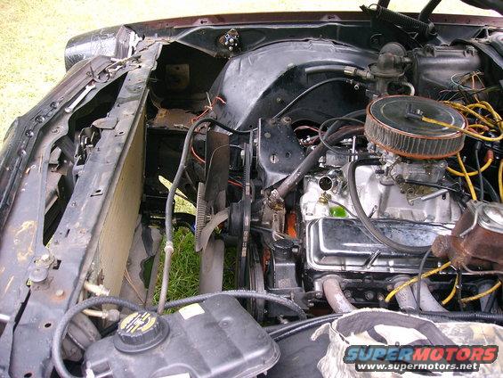 Engine bay with V8 engine, air filter, and radiator. Some text visible on coolant reservoir
