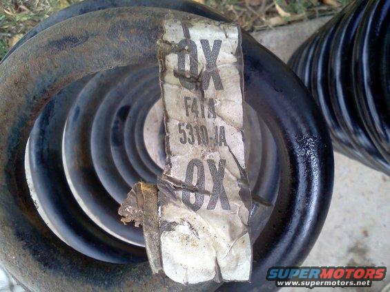 Two black coil springs, one with a torn label showing part numbers F41A 5310-JA
