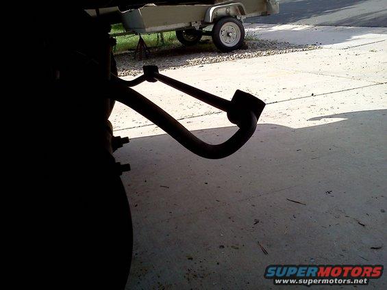 close-up of a curved metal suspension component attached to a vehicle's frame