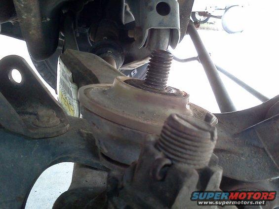 Close-up of a vehicle's suspension system, showing a coil spring seat and threaded bolt