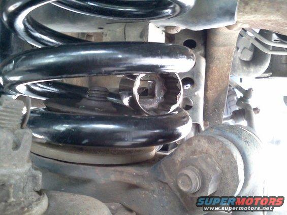 Close-up of a vehicle's suspension coil with a socket wrench inserted